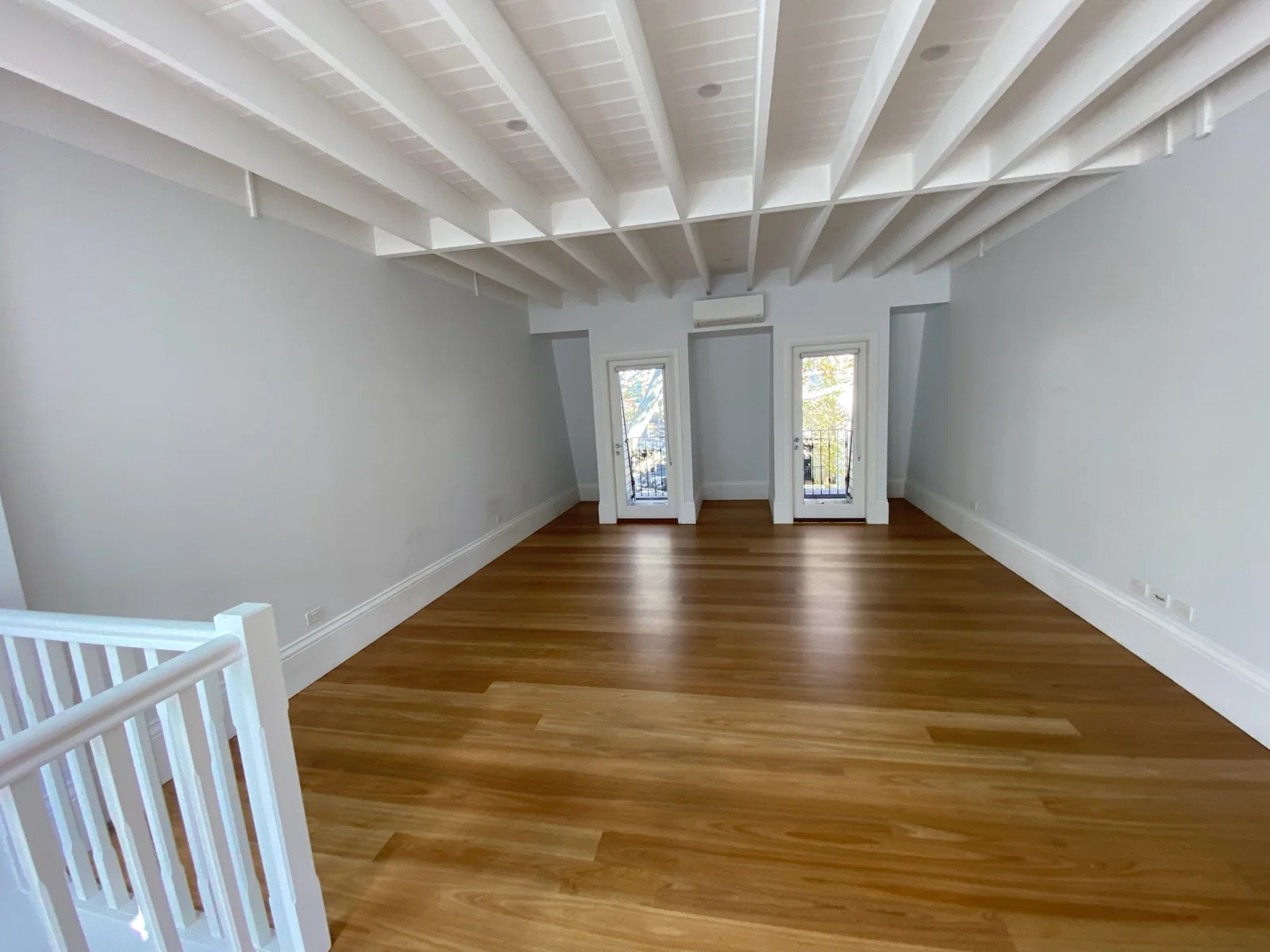 Fresh white exposed ceiling beams above a timber floor